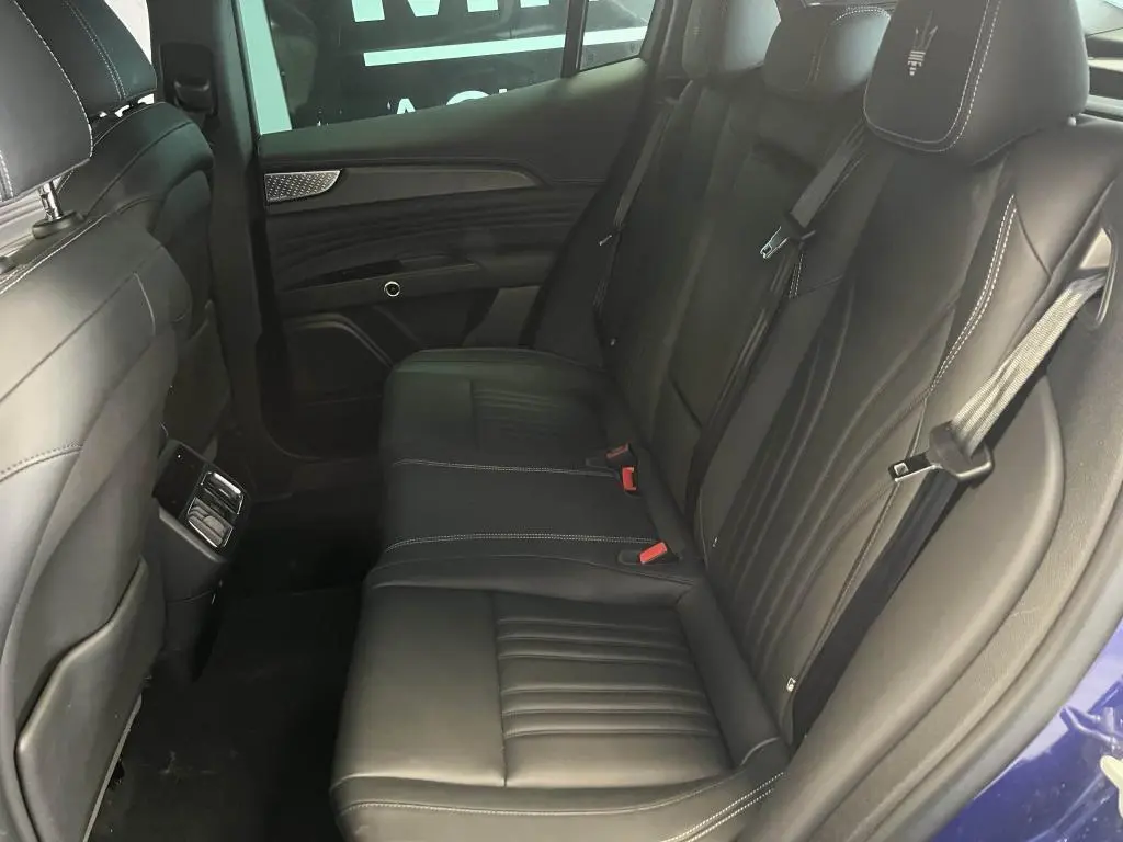 Vue intérieure côté droit des sièges arrière en cuir noir avec logo Trident brodé sur appuie-tête d'un Maserati Grecale bleu 2022.