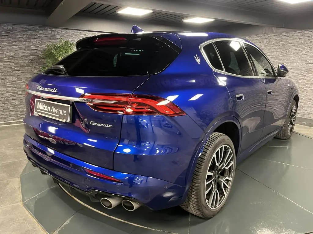 Vue 3/4 arrière droite du Maserati Grecale bleu avec jantes noires et double sortie d'échappement chromée.