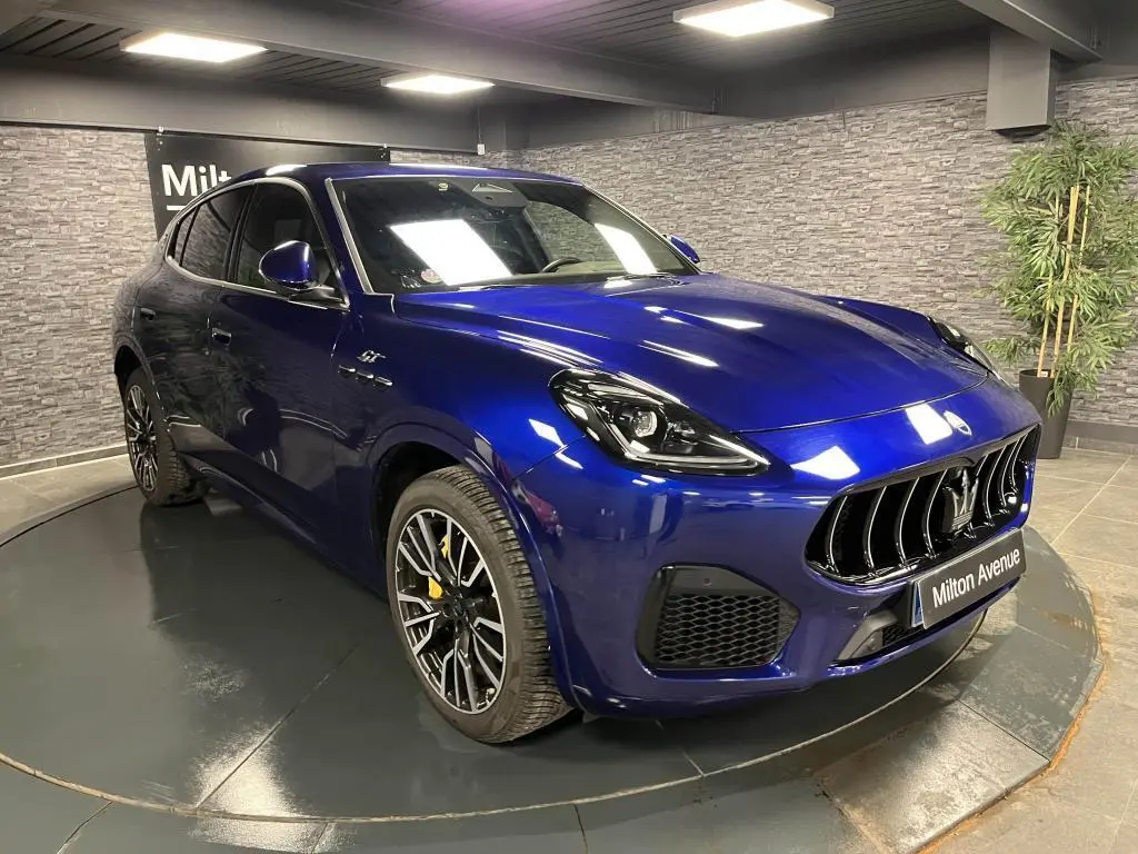 Vue 3/4 avant d'un Maserati Grecale bleu avec étriers de freins jaunes et jantes noires forgées en showroom.