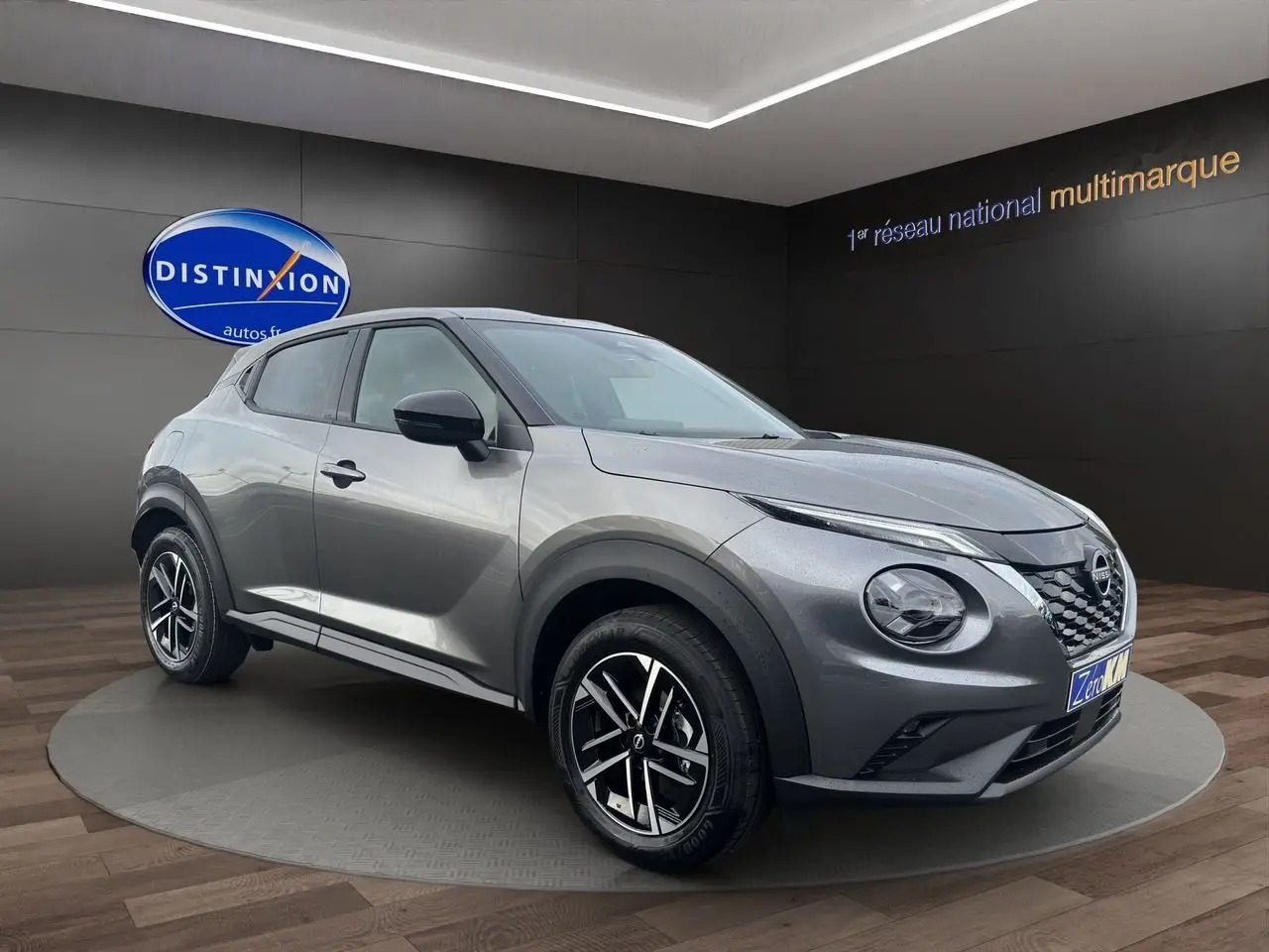Nissan Juke Full Hybrid gris squale en 3/4 avant droit, avec jantes alliage noires et calandre distinctive.