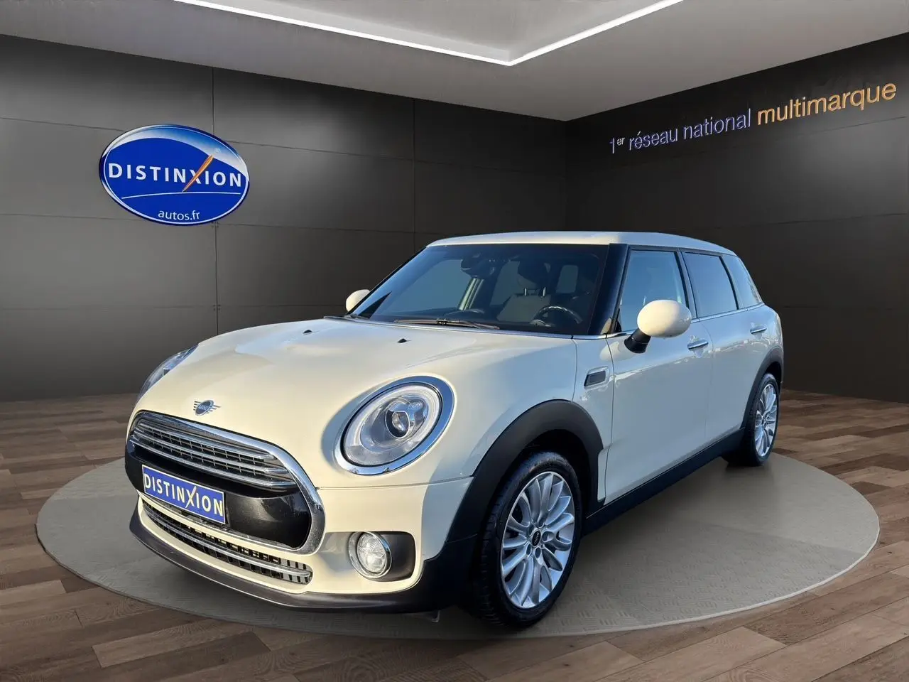 Mini Clubman F54 Cooper Exquisite blanc, vue 3/4 avant droit avec caméra de recul visible sur le hayon arrière.