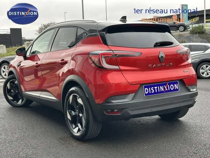 Vue 3/4 arrière droite du Renault Captur 2025 rouge flamme avec toit noir et jantes noires distinctives.
