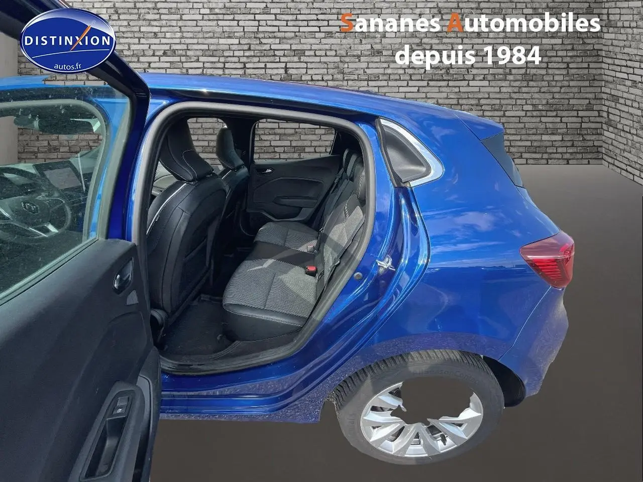 Vue côté gauche arrière d'une Renault Clio 2021 Bleu Iron avec porte arrière ouverte et sellerie noire en velours et cuir synthétique.