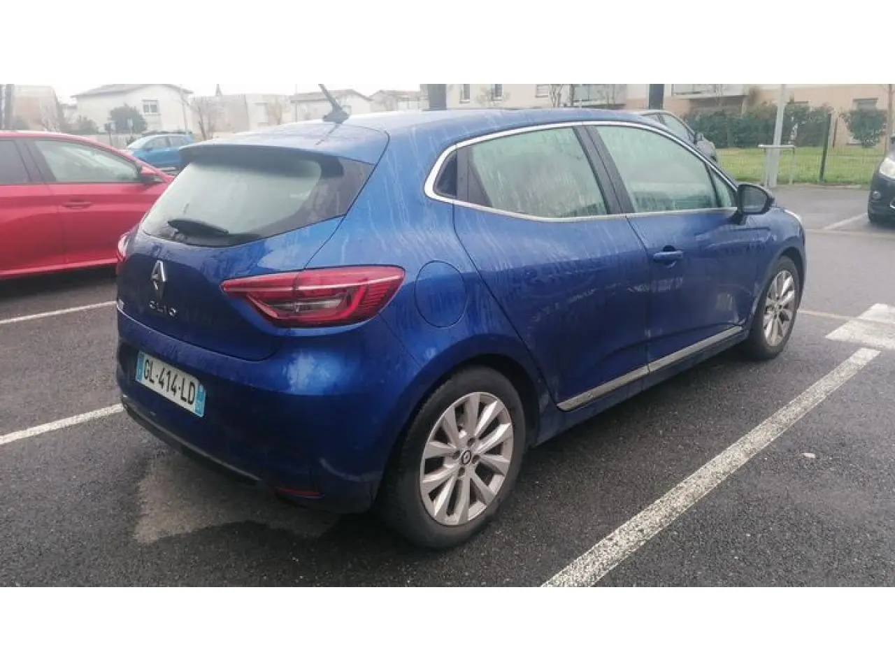 Renault Clio bleu Iron vue 3/4 arrière droit, garée sur parking avec jantes alliage et feux arrière LED.