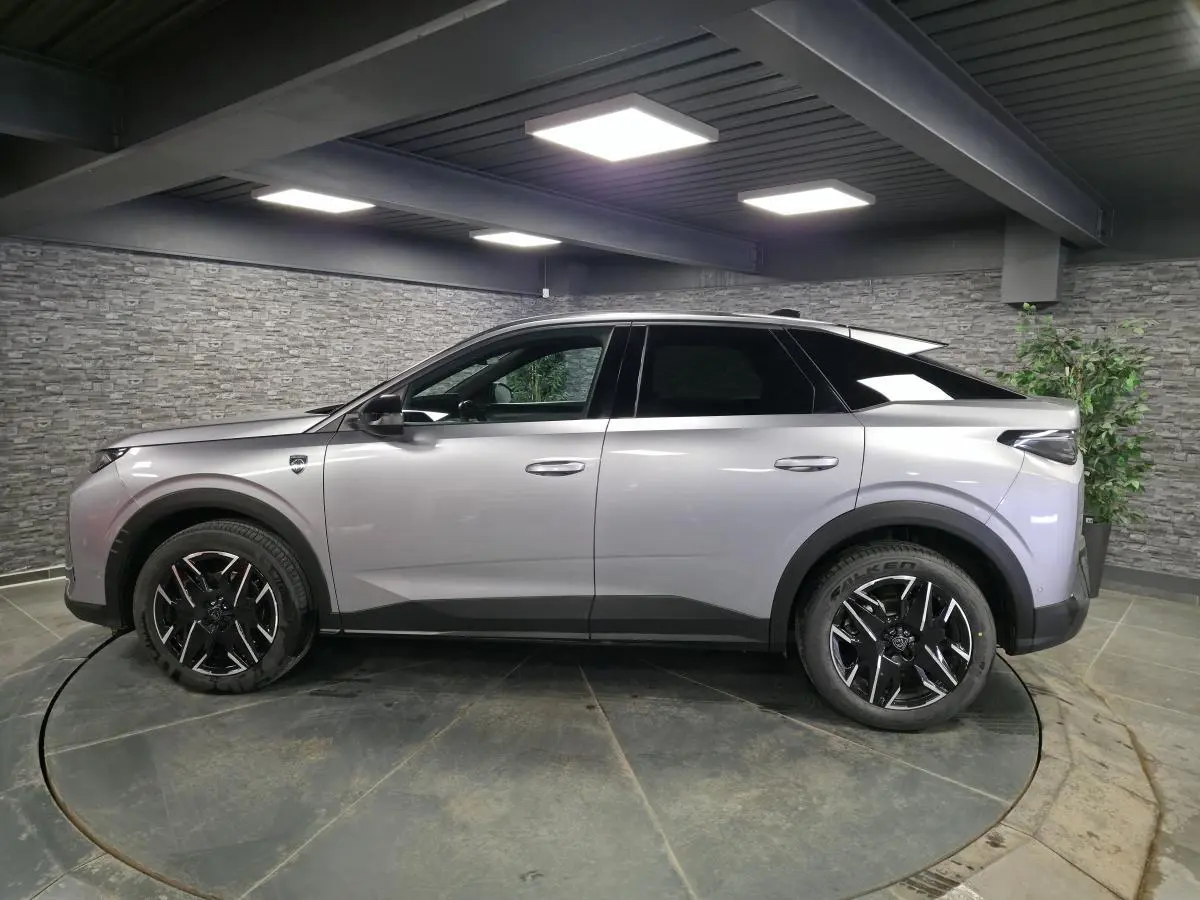 Peugeot 3008 gris en profil droit dans un showroom, avec jantes alliage noires et toit noir contrasté.