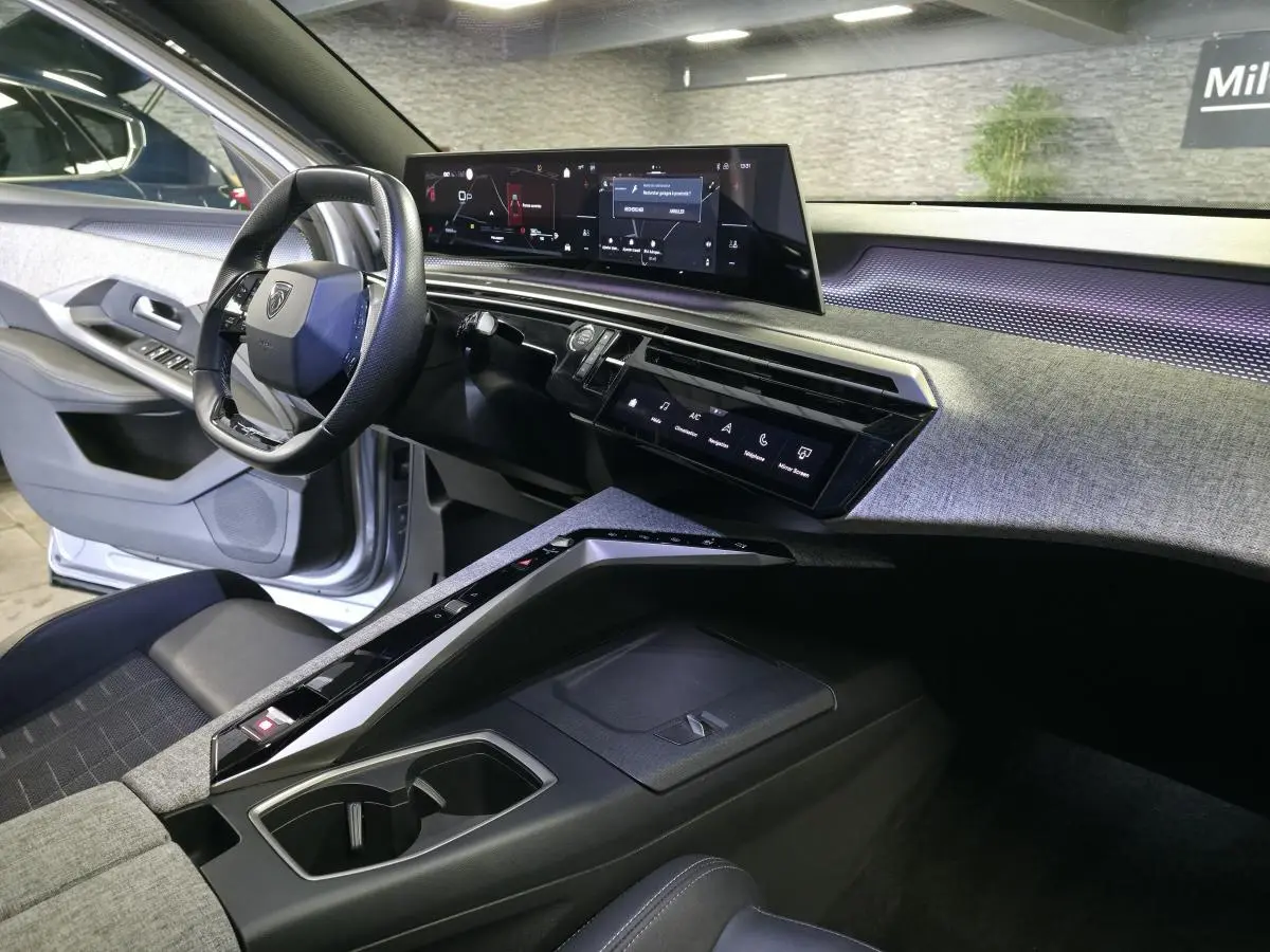 Vue intérieure côté conducteur du Peugeot 3008 gris 2025, avec tableau de bord numérique panoramique et console centrale design.