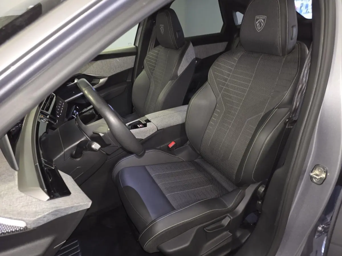 Vue intérieure côté conducteur du Peugeot 3008 gris 2025, sièges tissu et cuir avec logo GT brodé sur appuie-tête.