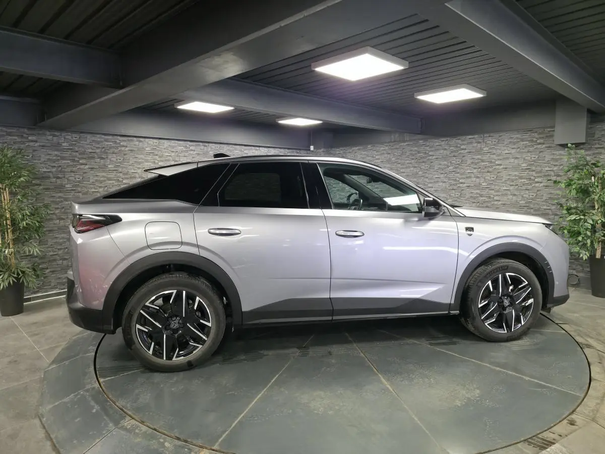 Vue latérale droite d’un Peugeot 3008 gris métallisé 2025 avec jantes alliage noires et toit noir contrasté.
