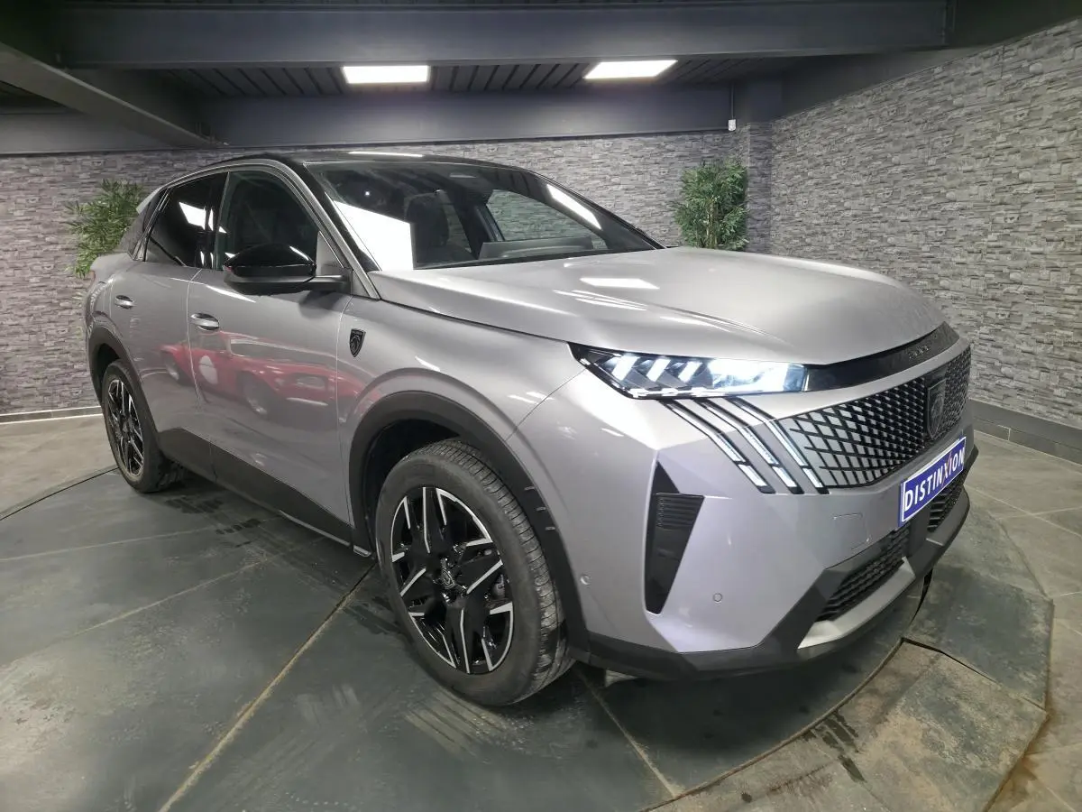Peugeot 3008 gris en 3/4 avant droit, avec calandre noire à motif géométrique et feux LED griffés.