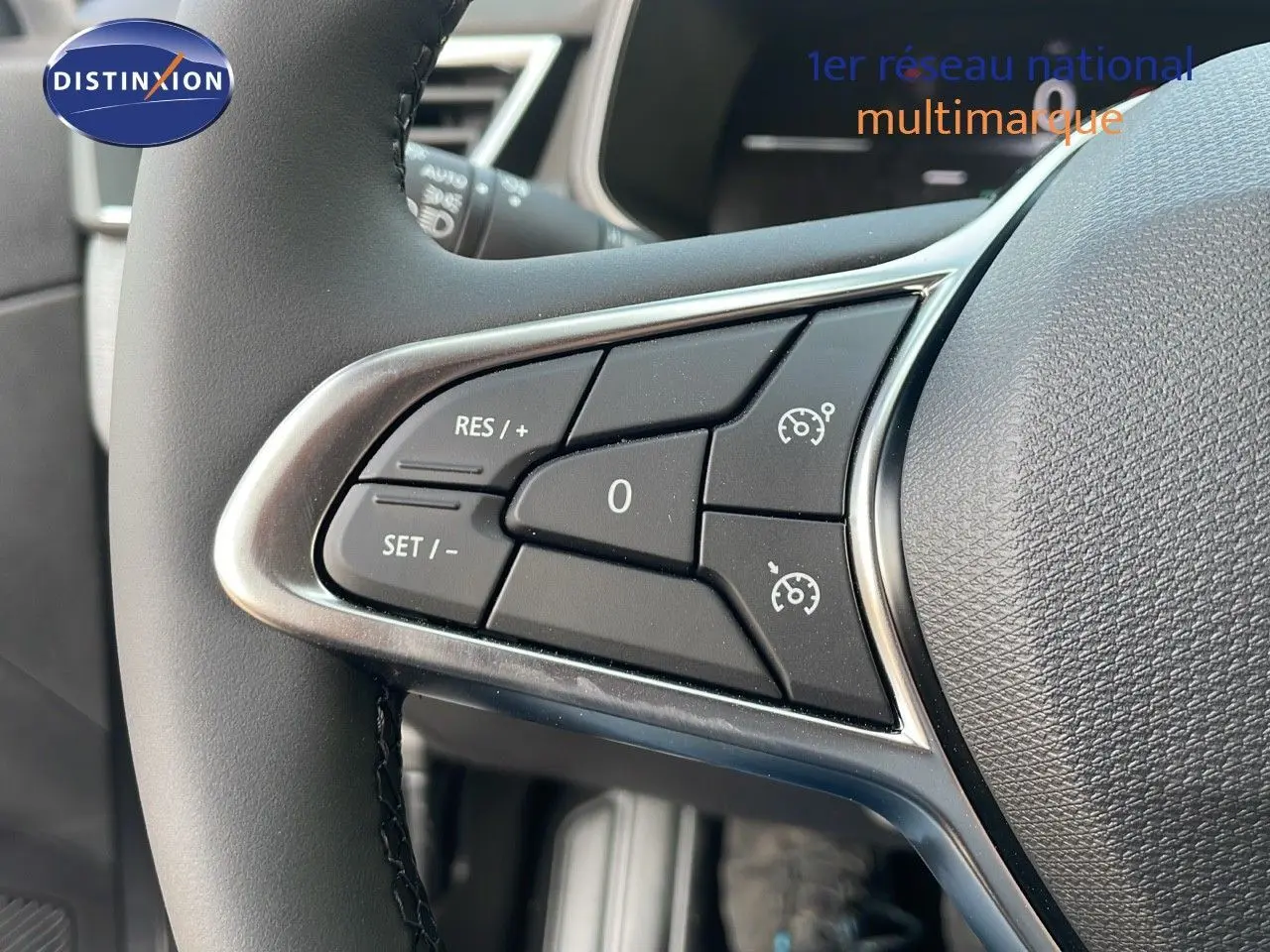 Gros plan sur les commandes de régulateur de vitesse au volant cuir d'une Renault Clio gris schiste métal, intérieur gris-noir.