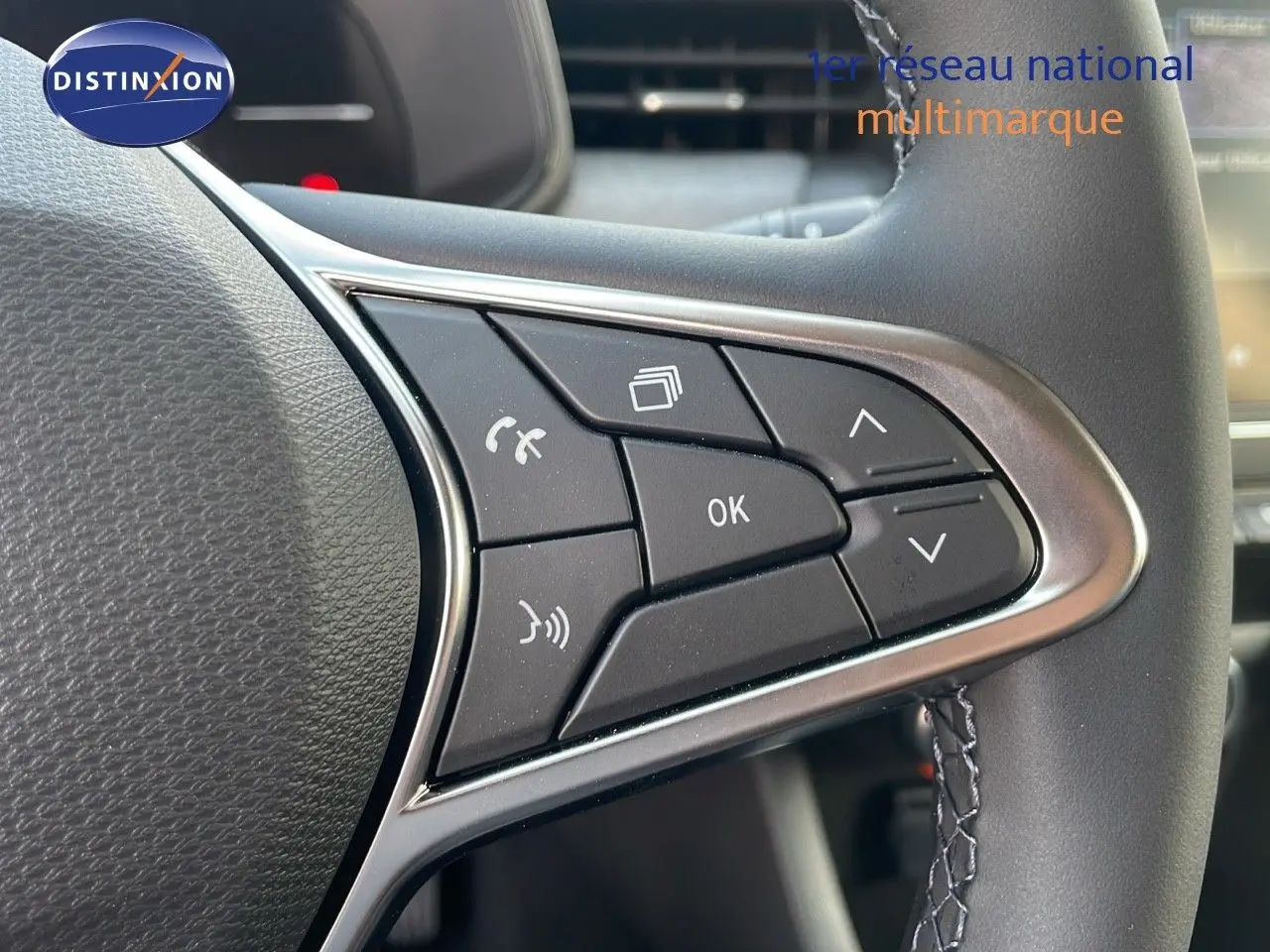 Gros plan sur les commandes au volant cuir de la Renault Clio 2025, finition gris schiste métal, boutons multifonctions visibles.