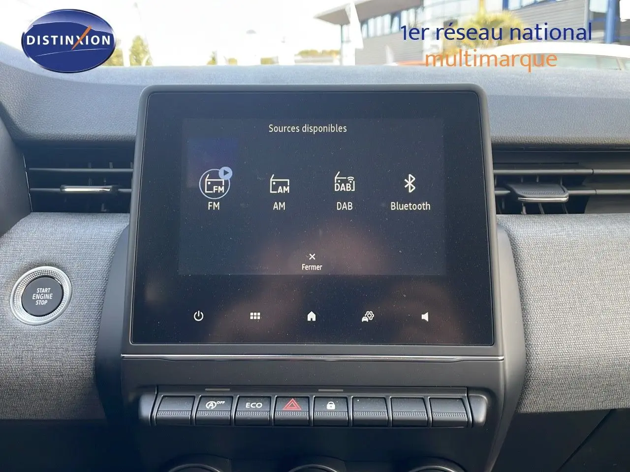 Tableau de bord de Renault Clio 2025, écran tactile central affichant les sources audio, finition tissu gris clair.