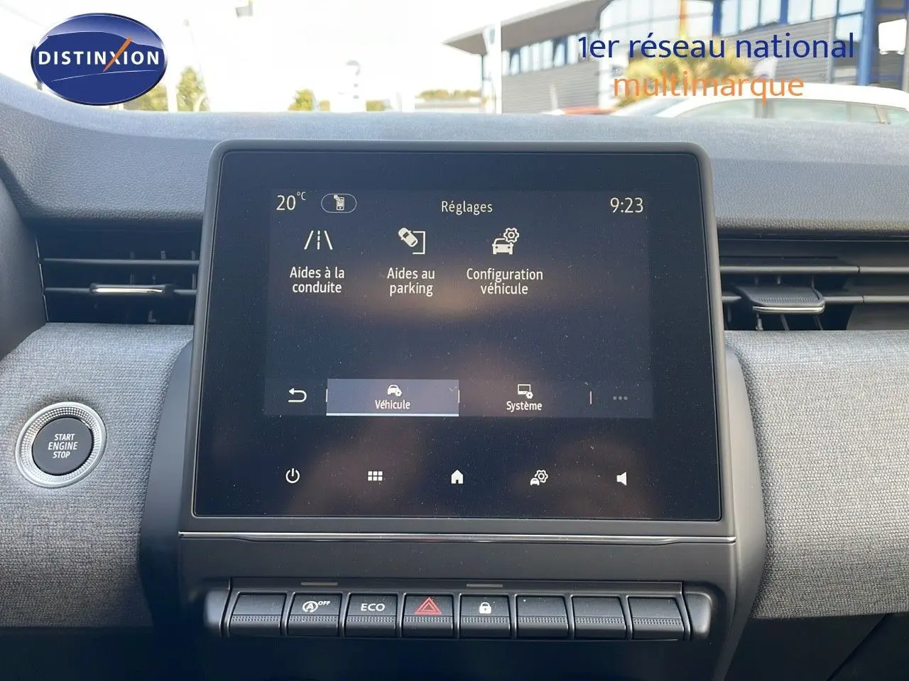 Vue intérieure centrée sur l’écran tactile du tableau de bord de la Renault Clio gris schiste, avec bouton start visible à gauche.