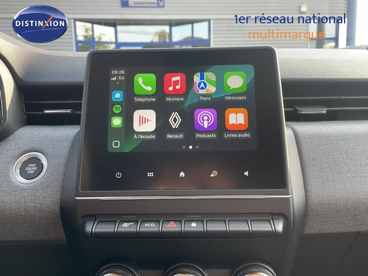 Vue rapprochée de l’écran tactile central de la Renault Clio gris schiste, avec commandes et bouton start/stop visibles.