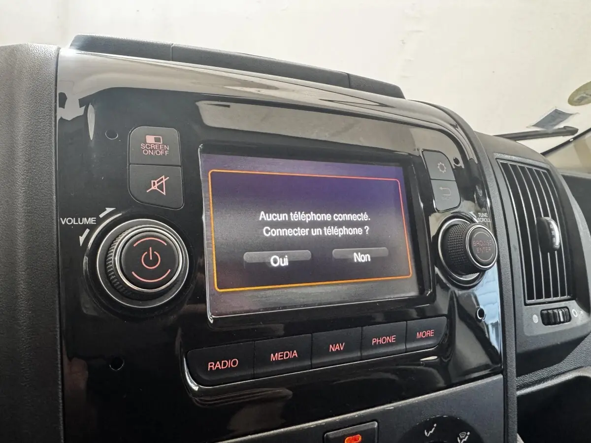 Gros plan sur l’écran tactile multimédia noir du tableau de bord du Citroën Jumper blanc, affichant une connexion téléphone.