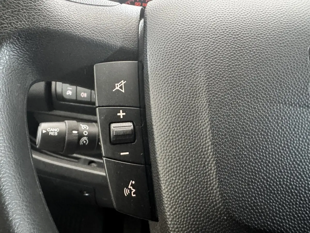 Gros plan sur le volant multifonctions noir du Citroën Jumper 2023, avec commandes de volume et de son.