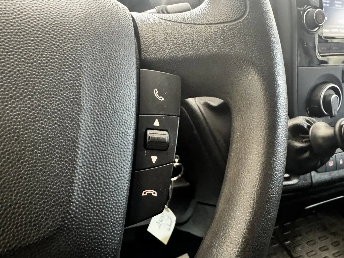 Gros plan sur le volant multifonctions noir du Citroën Jumper 33 L1H1, avec commandes d’appel intégrées.