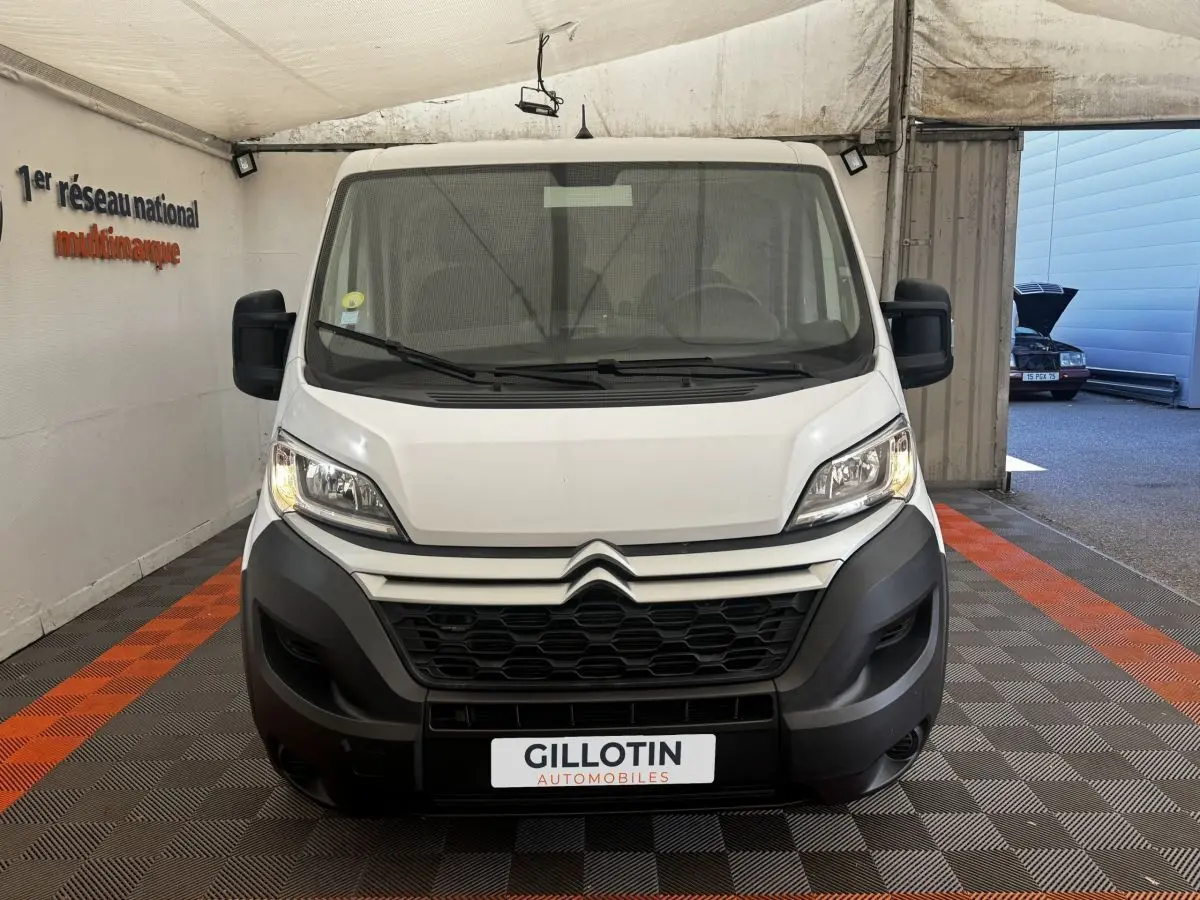 Vue frontale d’un Citroën Jumper blanc 2023 avec calandre noire et phares allumés dans un garage.