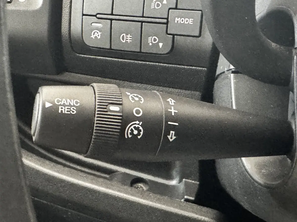 Gros plan sur la commande de régulateur de vitesse à gauche du volant dans l’habitacle du Citroën Jumper blanc 2023.