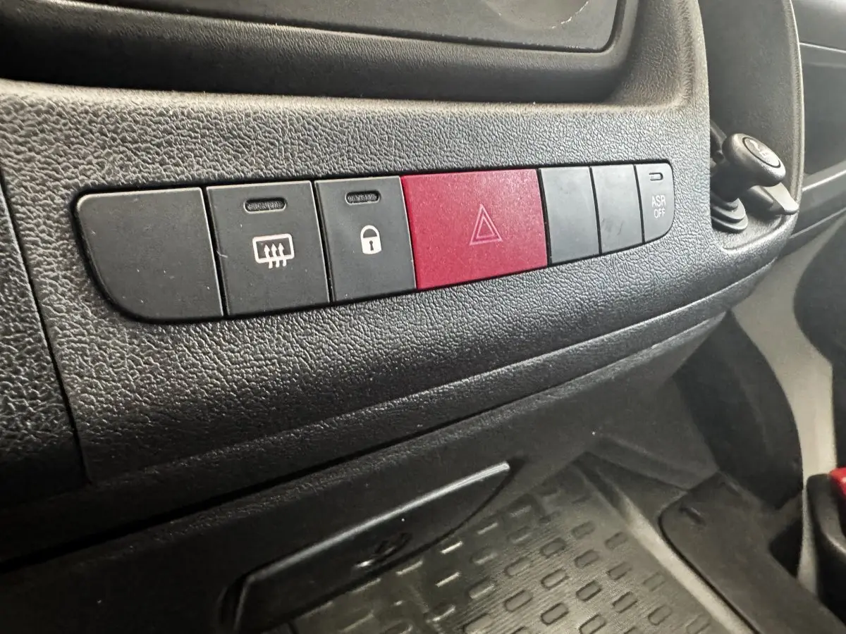 Gros plan sur la rangée de boutons noirs et rouge du tableau de bord du Citroën Jumper 2023, intérieur noir.