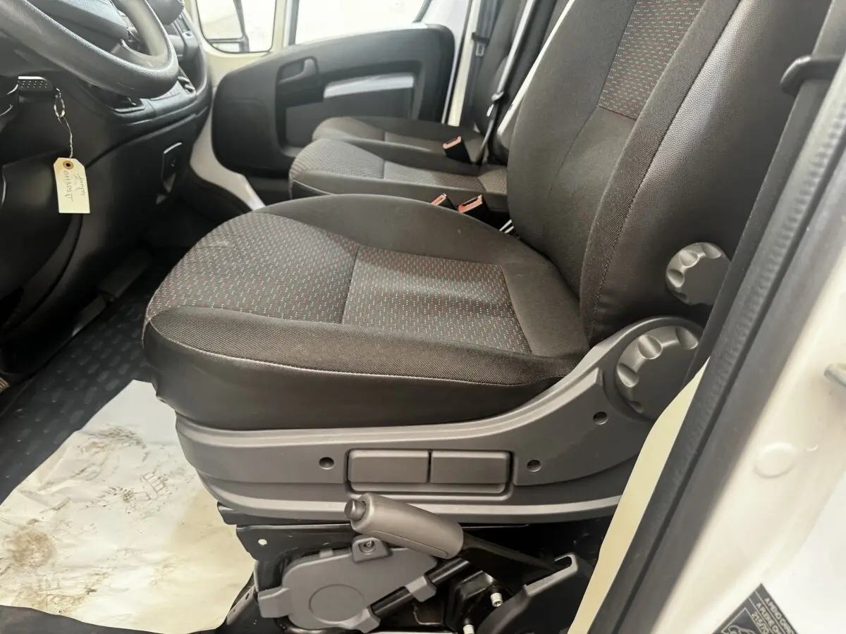 Vue intérieure côté conducteur du siège avant noir avec réglages manuels du Citroën Jumper blanc 2023.