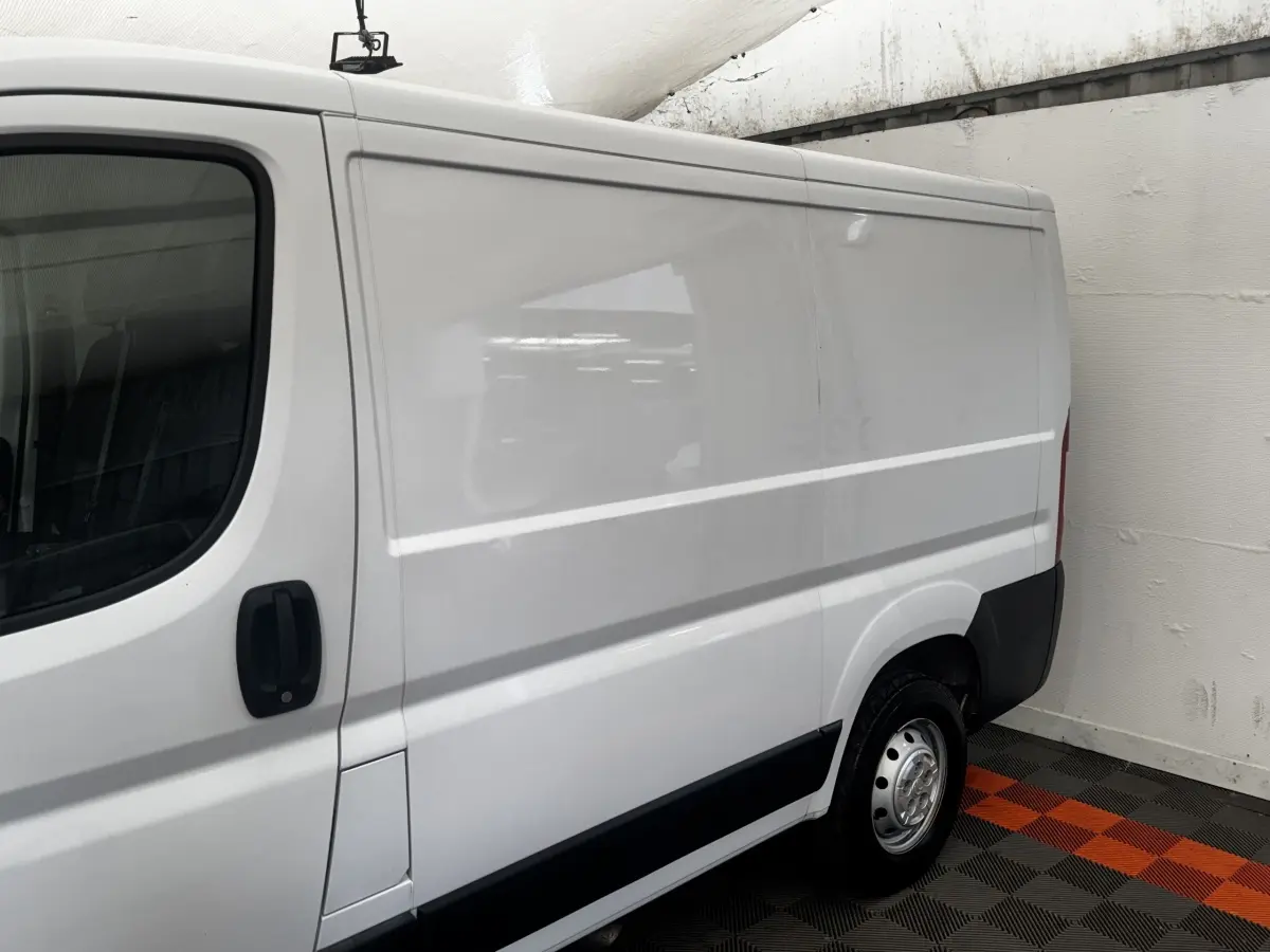 Vue latérale droite d’un utilitaire blanc Citroën Jumper 33 L1H1 avec porte coulissante et jante acier.