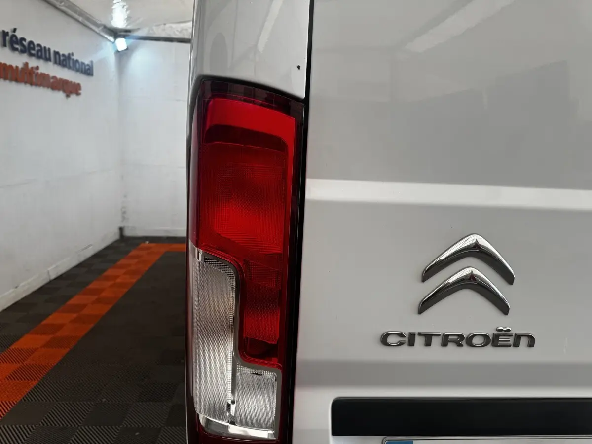 Gros plan sur le feu arrière gauche d’un utilitaire blanc Citroën Jumper, avec logo visible sur la porte arrière.