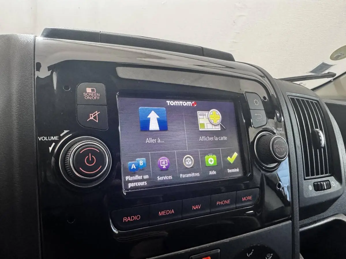 Écran tactile central allumé avec interface TomTom, tableau de bord noir brillant du Citroën Jumper blanc 2023.