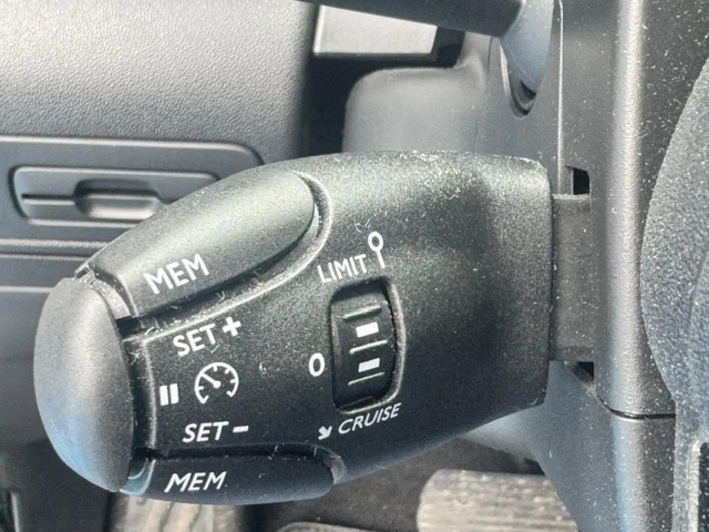 Gros plan sur la commande de régulateur de vitesse noire dans l'habitacle du Citroën C3 Aircross gris acier.