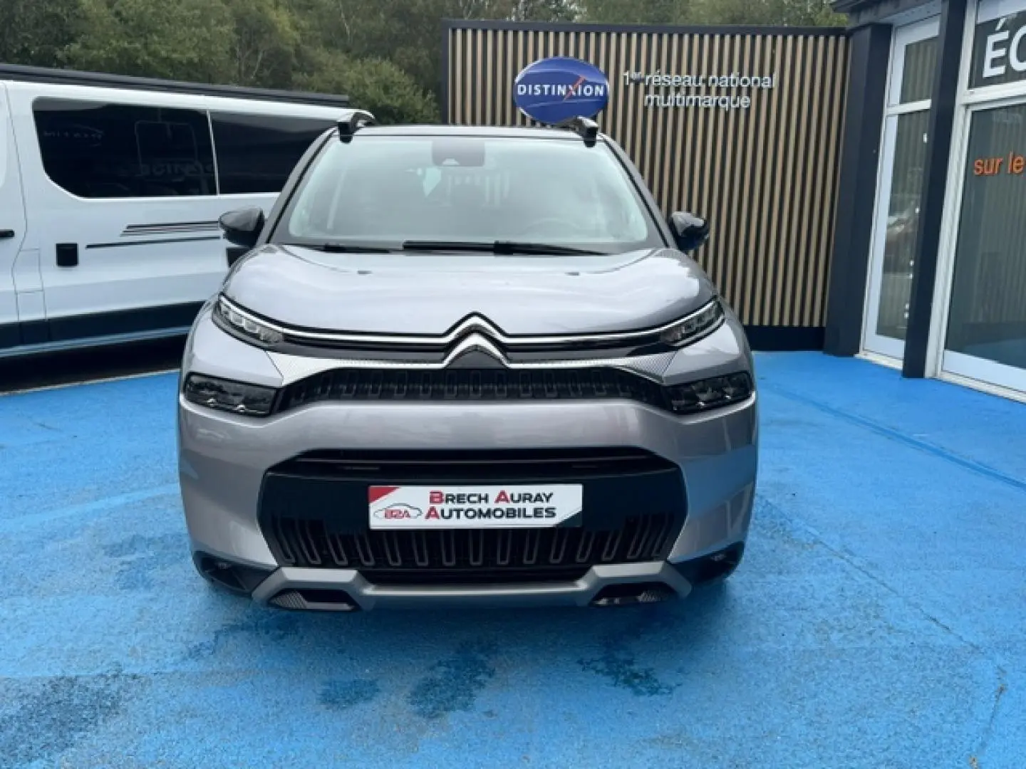 Vue avant d'un Citroën C3 Aircross 2024 gris acier avec calandre noire et barres de toit visibles.