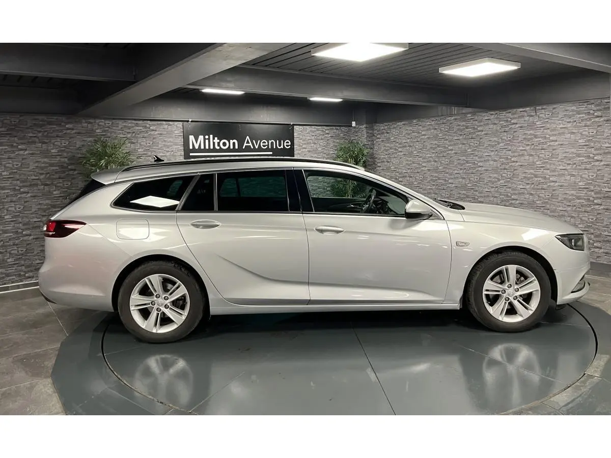 Profil côté gauche d'une Opel Insignia Sports Tourer gris métallisé dans un showroom avec jantes alliage 5 branches.