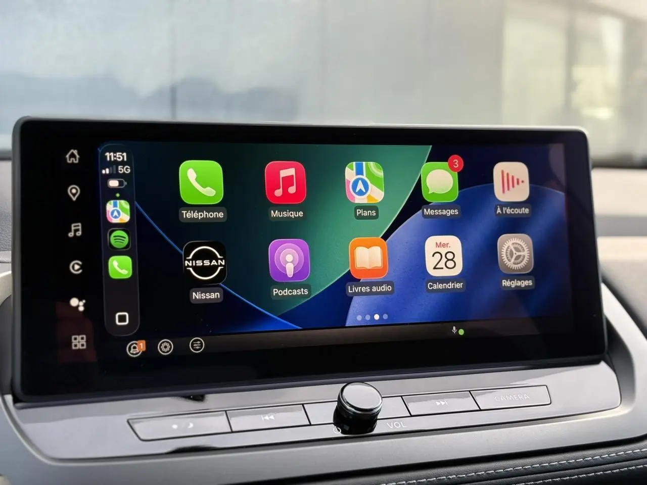 Écran tactile intérieur du Nissan Qashqai blanc nacré, affichant Apple CarPlay avec icônes colorées.