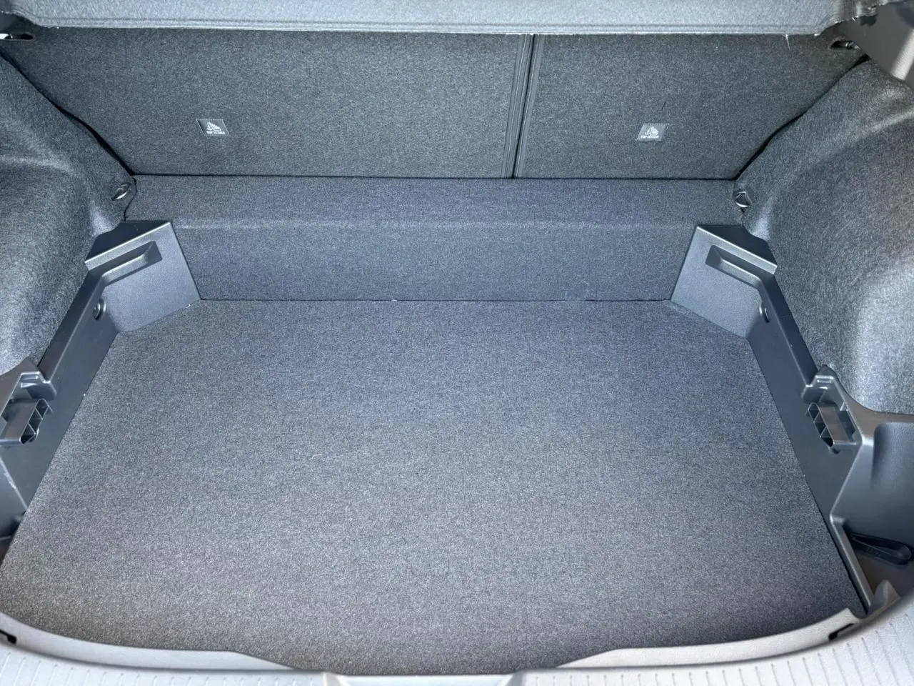 Vue plongeante sur le coffre spacieux et vide du Nissan Qashqai blanc nacré, revêtement gris foncé uniforme.