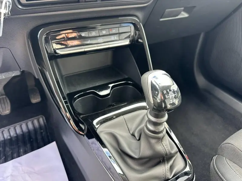 Gros plan sur la console centrale noire de la Citroën C3 2025, mettant en valeur le levier de vitesse manuel et les commandes climatiques.