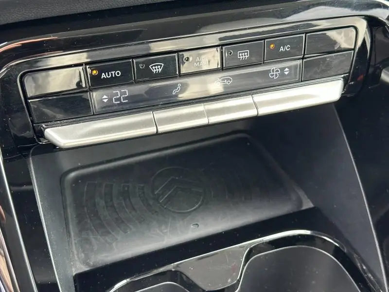 Vue rapprochée de la console centrale noire du Citroën C3 2025, avec commandes climatisation et surface de recharge sans fil.
