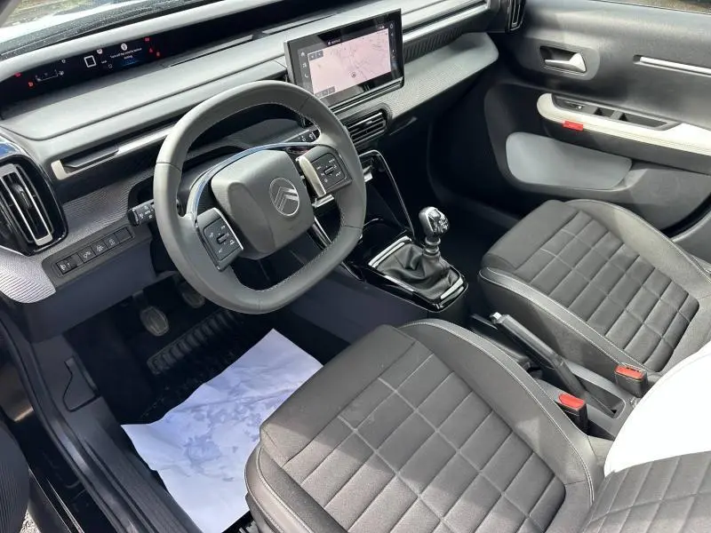 Vue intérieure côté conducteur de la Citroën C3 1.2 Turbo 100ch MAX 2025 avec sièges noirs et écran tactile central.