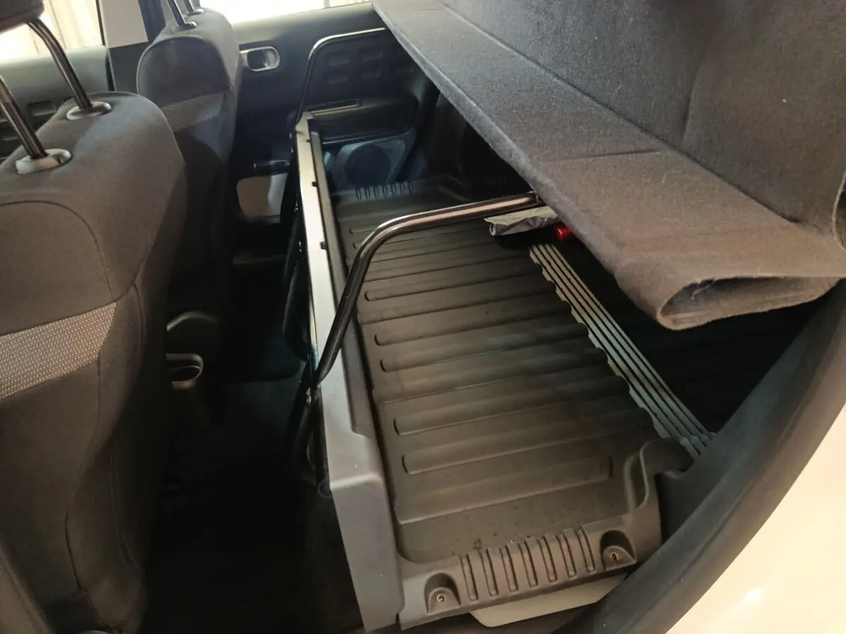 Vue intérieure arrière côté droit du coffre modulable de la Citroën C3 blanche avec banquette relevée.