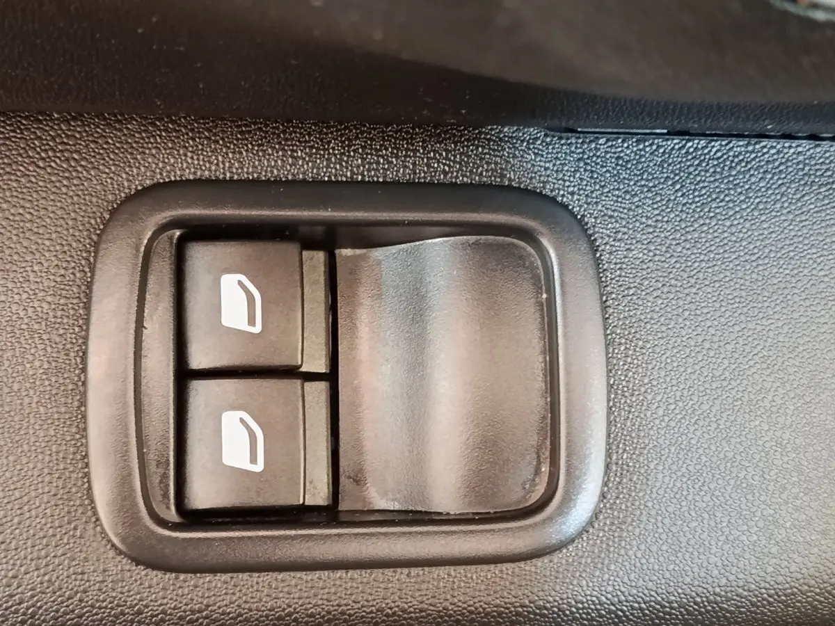 Gros plan sur les boutons de commande des vitres électriques côté conducteur d’une Citroën C3 blanche.