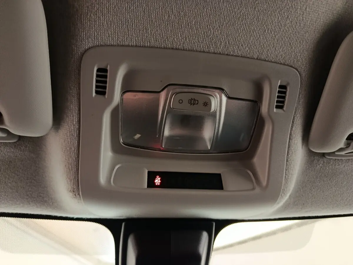Gros plan sur le plafonnier intérieur avec éclairage et témoin de ceinture allumé dans une Citroën C3 blanche.