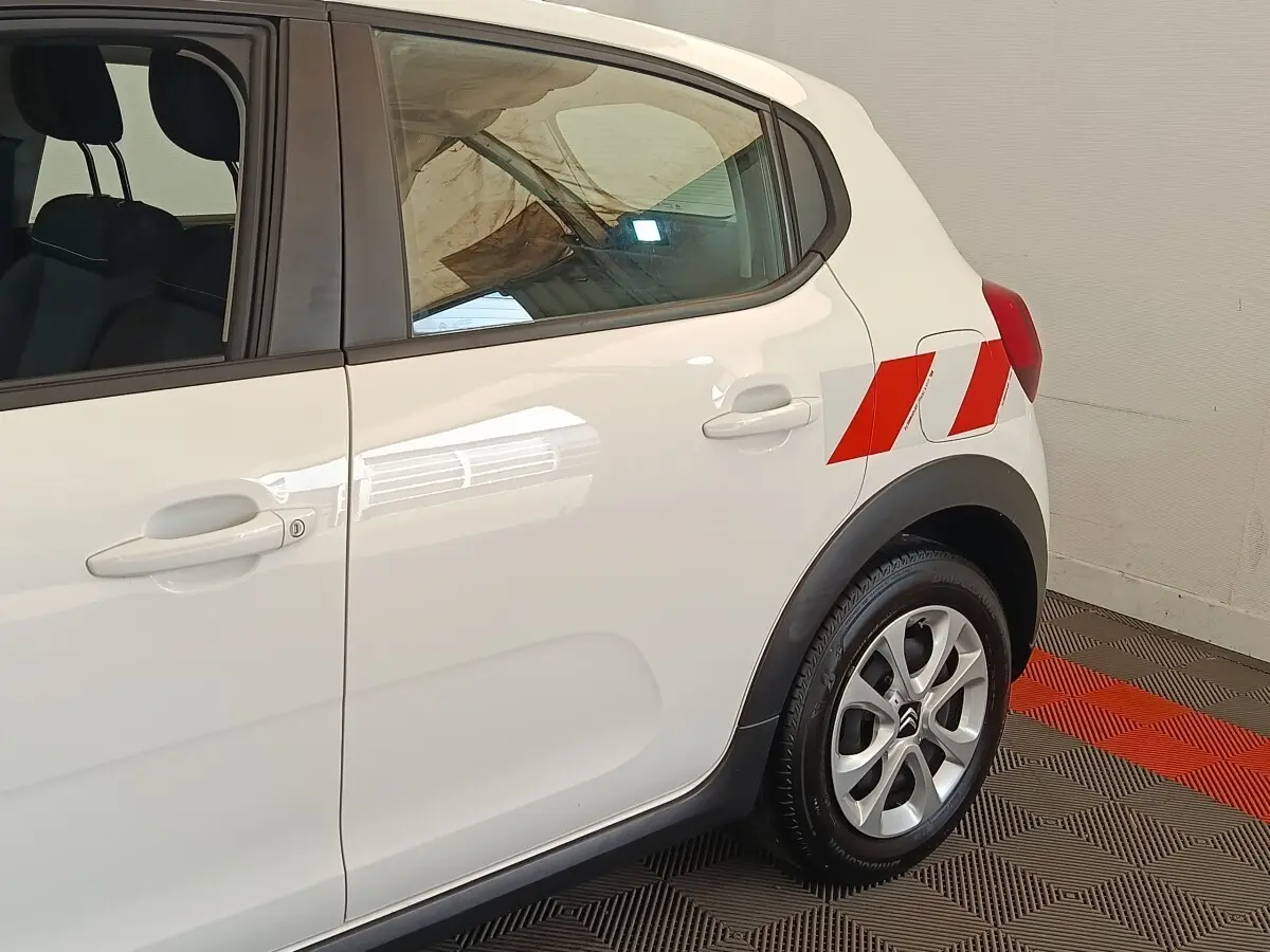 Vue latérale droite d'une Citroën C3 blanche 2021 avec marquages rouges sur l'aile arrière et jantes alliage.