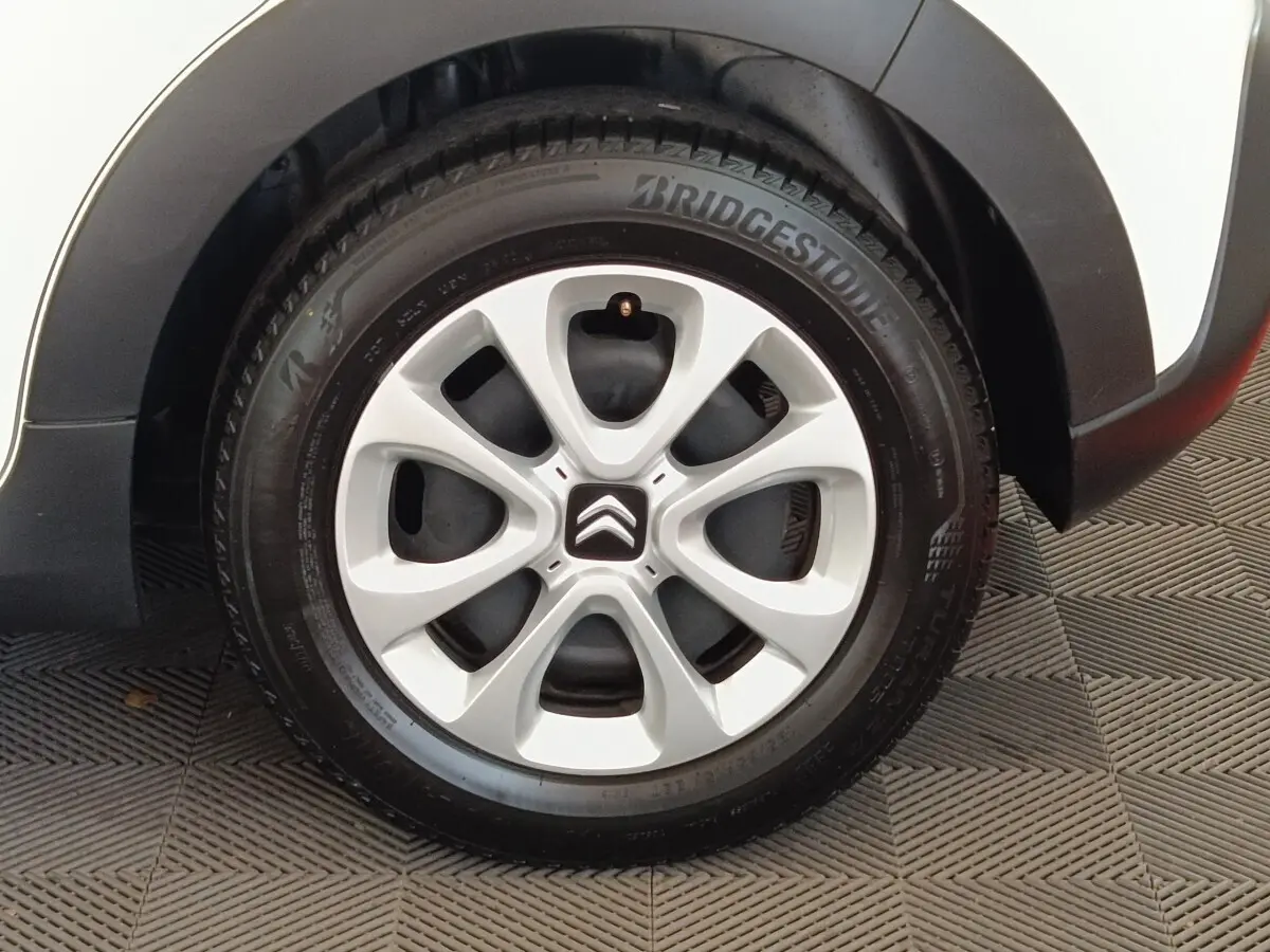 Gros plan sur la roue avant droite blanche d'une Citroën C3 2021 avec jante en alliage et logo Citroën central.