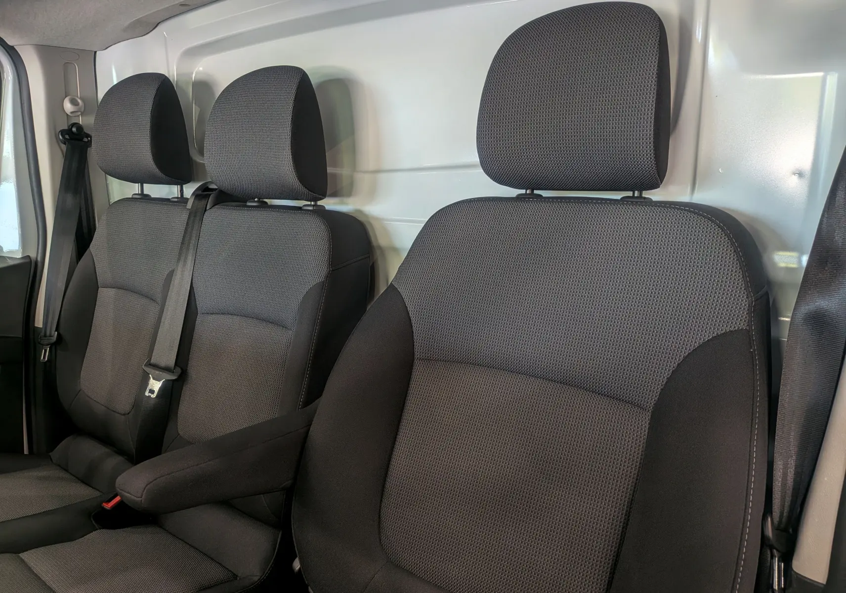 Vue rapprochée des sièges avant en tissu gris foncé du Renault Trafic Fourgon Blanc Minéral 2024, version Advance.