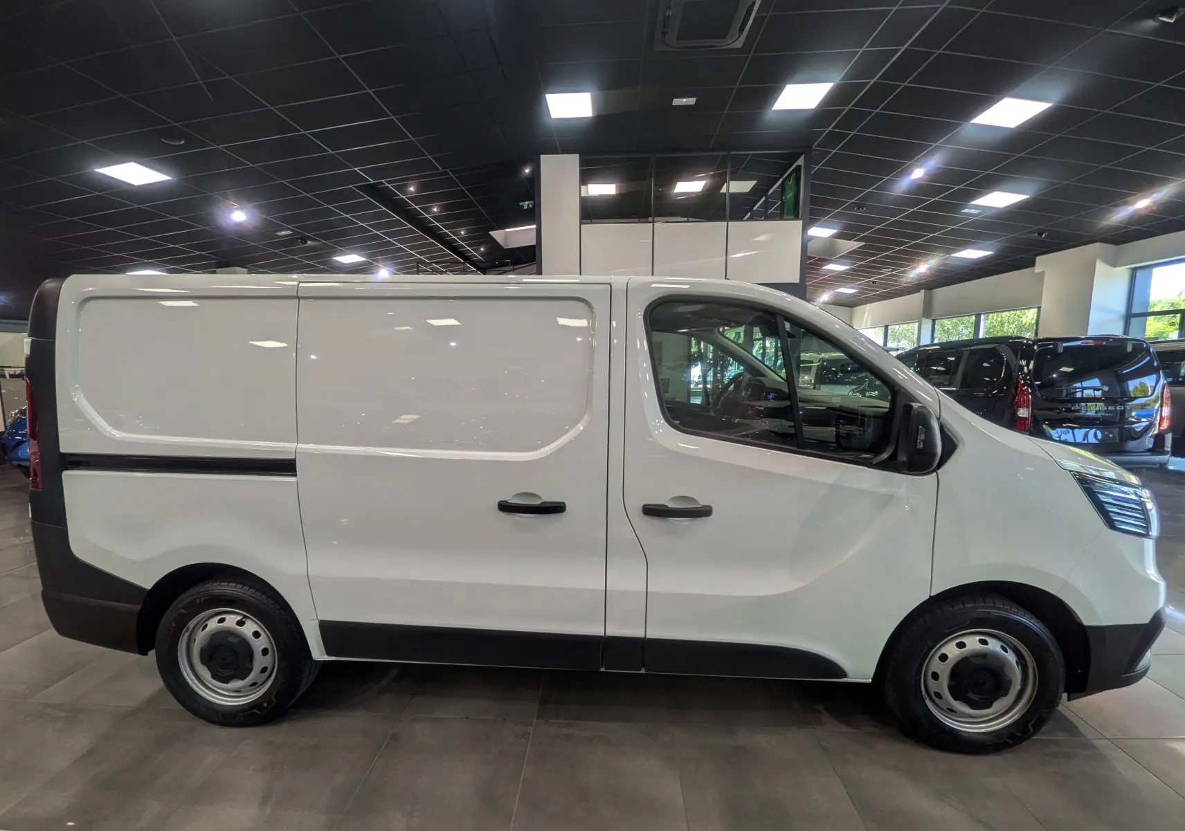 Vue de profil côté droit du Renault Trafic Fourgon blanc minéral 2024, version Blue dCi avec portes latérales et jantes acier.