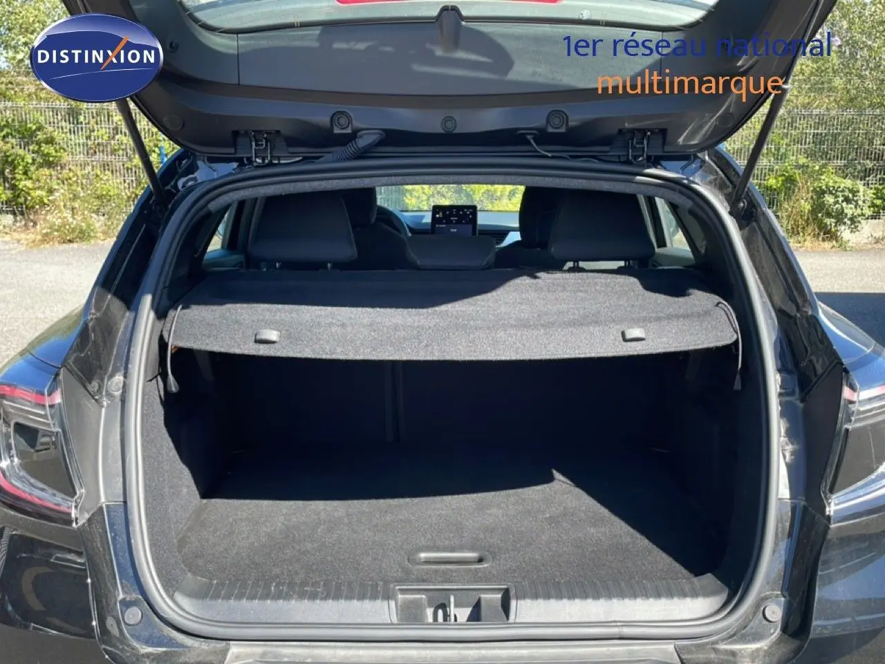 Coffre ouvert vu de l'arrière d'un Renault Captur noir étoile métal, montrant l'espace de chargement et la tablette arrière.