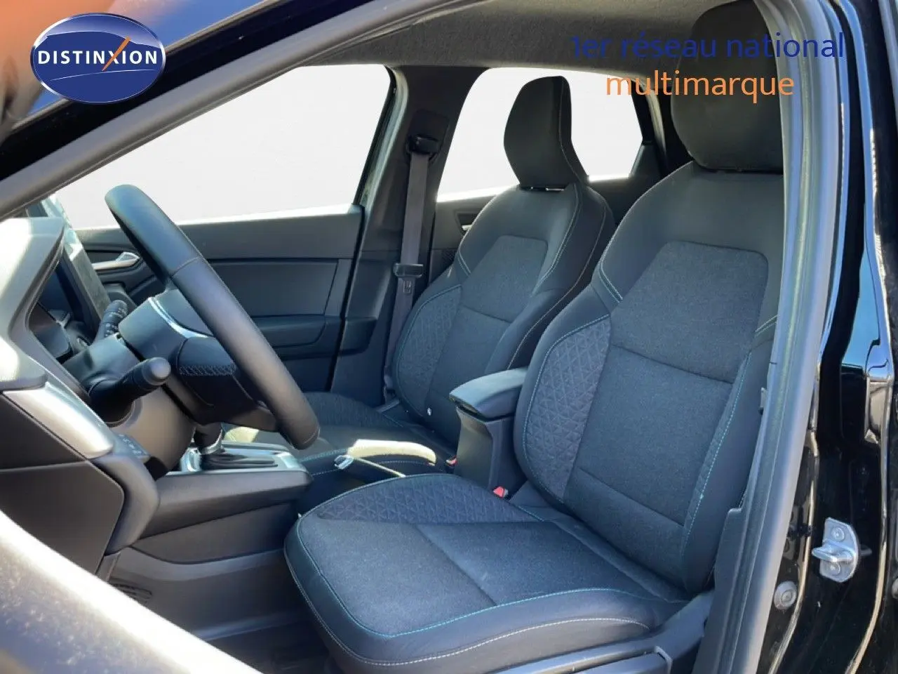 Vue intérieure côté conducteur du Renault Captur E-Tech Full Hybrid 2025, sièges tissu noir étoile métal avec surpiqûres bleues.