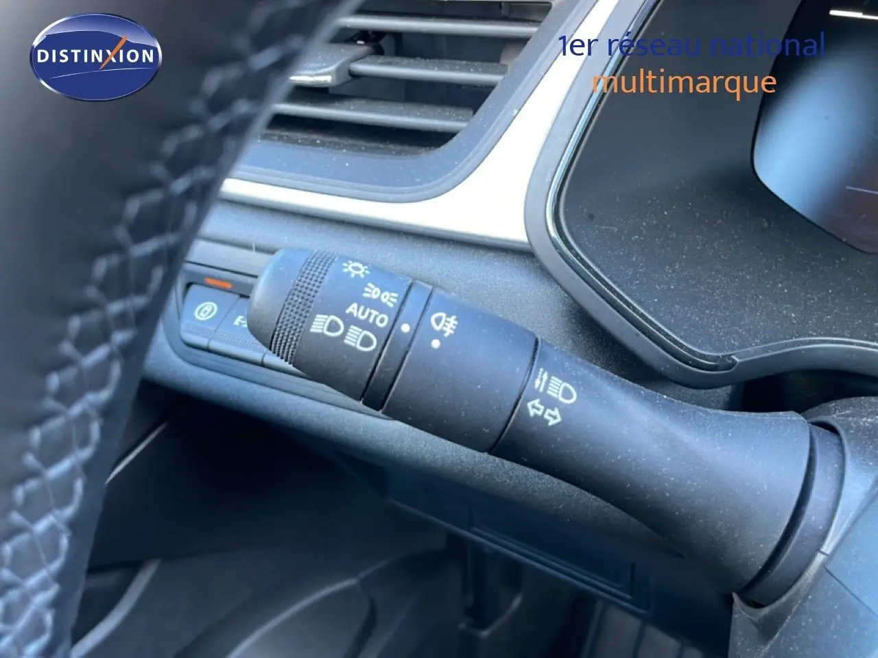 Gros plan sur la commande des phares et clignotants à gauche du volant dans l'habitacle noir du Renault Captur hybride.