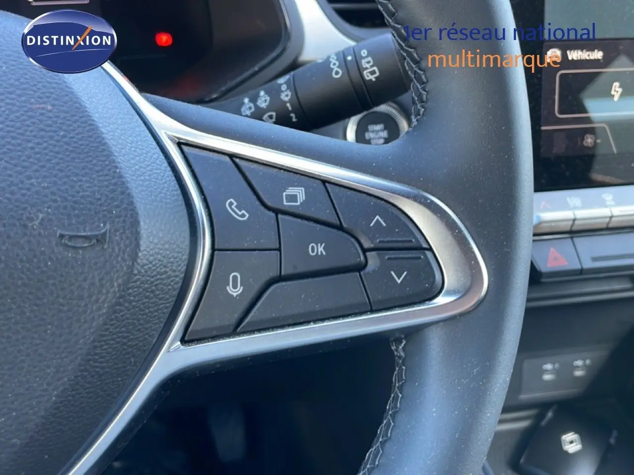 Gros plan sur les commandes multifonctions à droite du volant cuir noir du Renault Captur E-Tech 2025, avec tableau de bord partiel.
