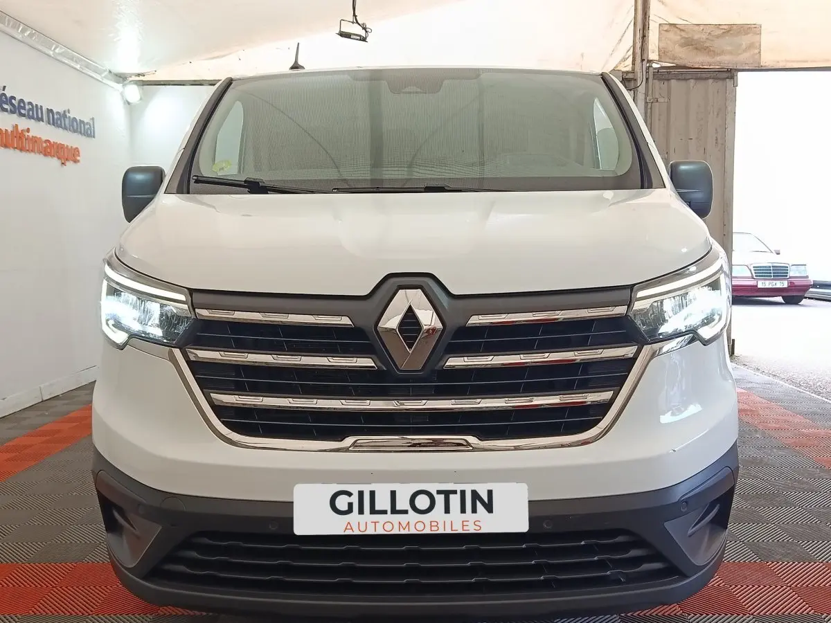 Vue frontale d’un Renault Trafic Fourgon blanc 2023 avec calandre chromée et feux LED allumés.