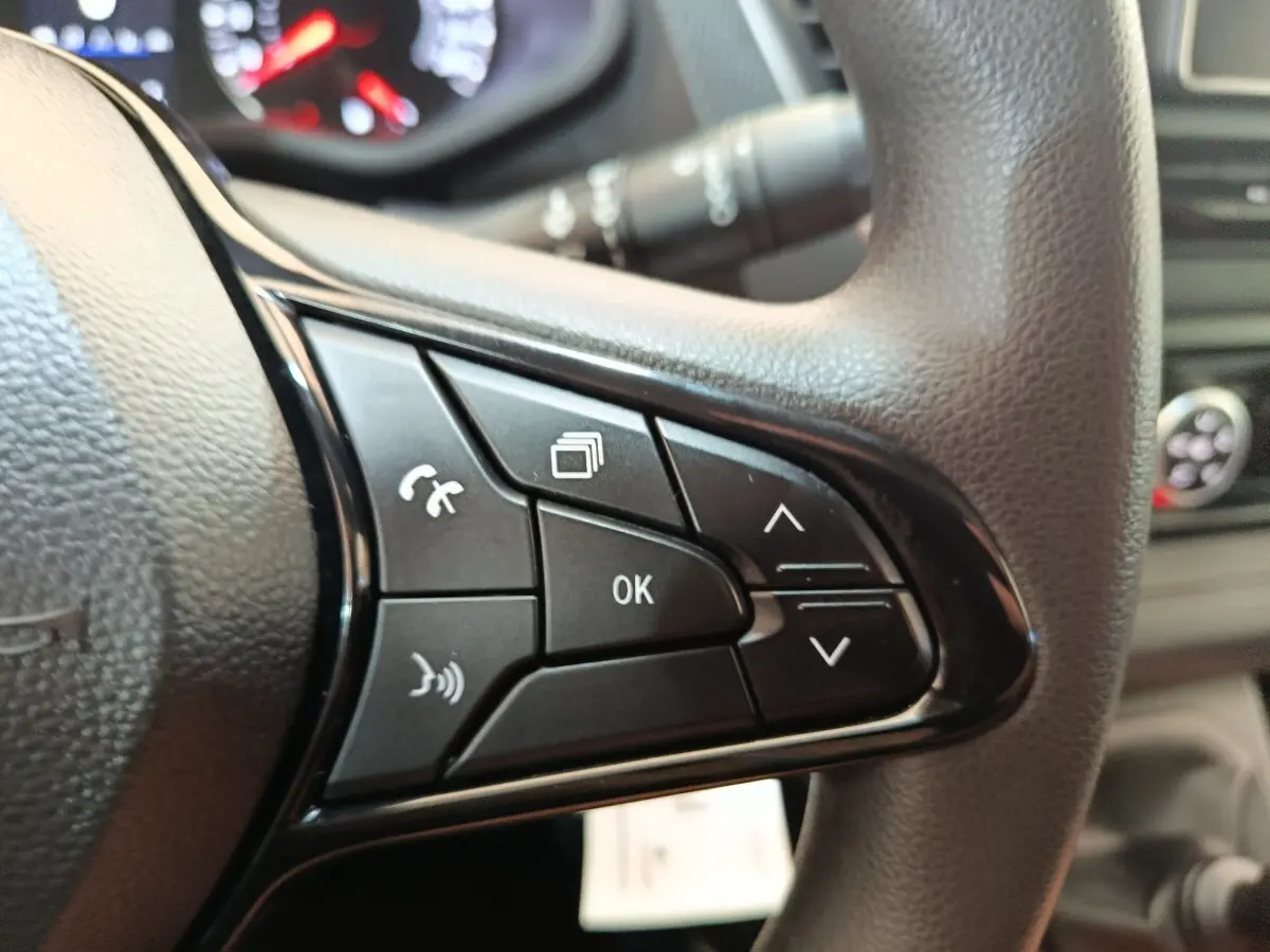 Gros plan sur les commandes multifonctions noires du volant du Renault Trafic Fourgon blanc, version 2023.
