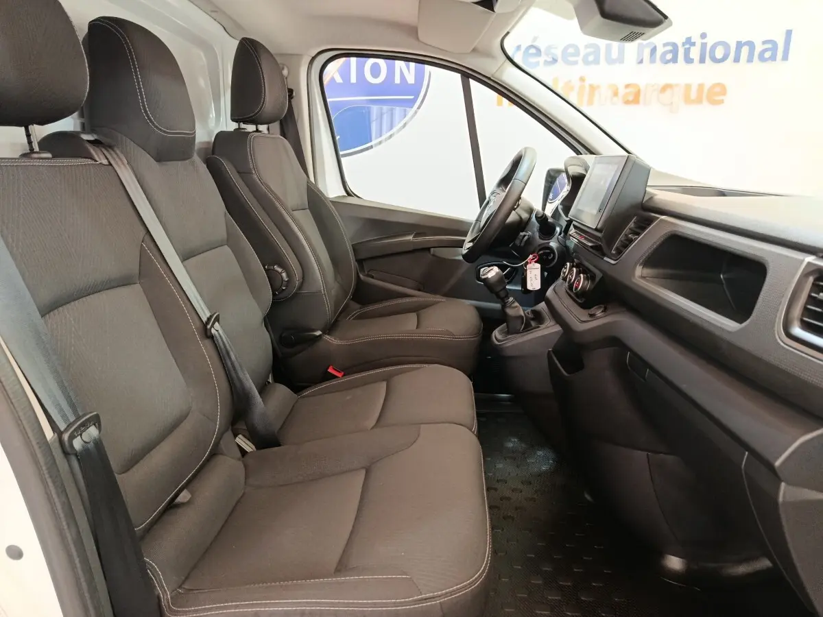 Vue intérieure côté droit du Renault Trafic Fourgon 2023, montrant les sièges noirs et le tableau de bord avec volant multifonctions.